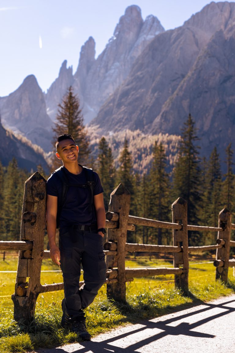 Daniel standing on fence near mountains